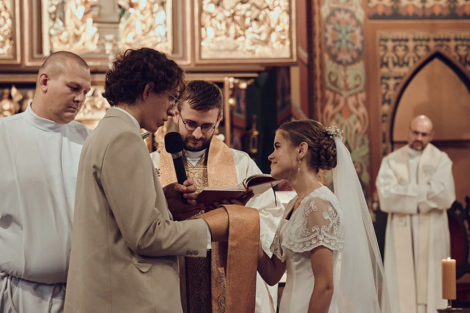 Para młoda podczas ceremonii ślubnej wypowiada przysięgi przed księdzem w kościele.
