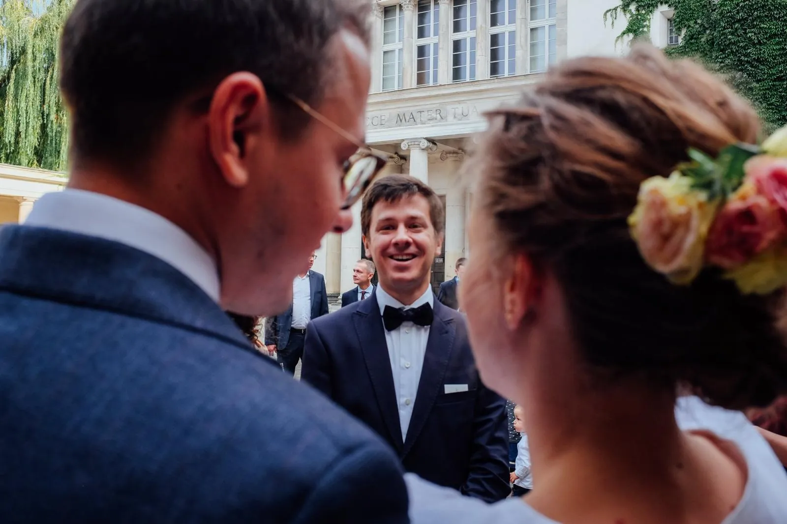 Radość po ślubie, para młoda śmieje się z gośćmi przed kościołem.