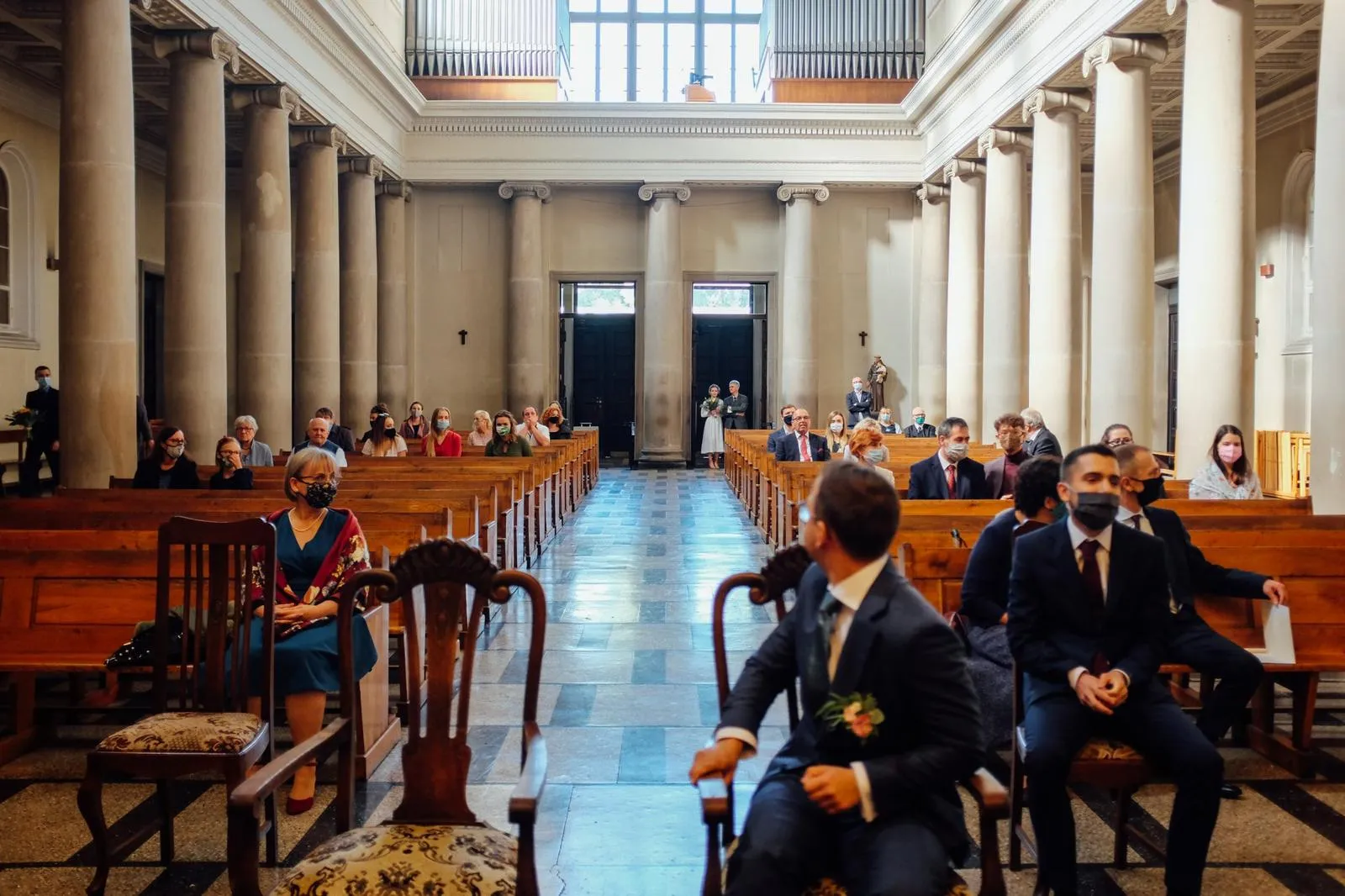 Panna młoda wchodzi do kościoła, w tle czekający goście – moment tuż przed ceremonią ślubu.