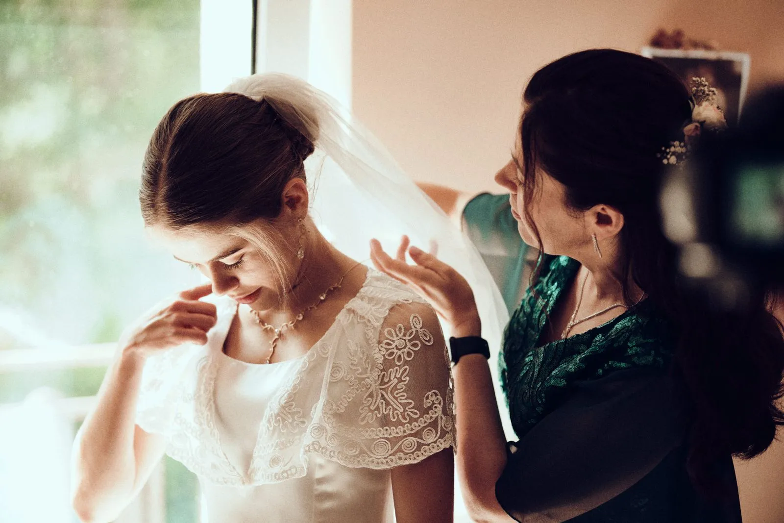 Panna młoda podczas przygotowań do ślubu, otrzymuje pomoc przy zakładaniu welonu.