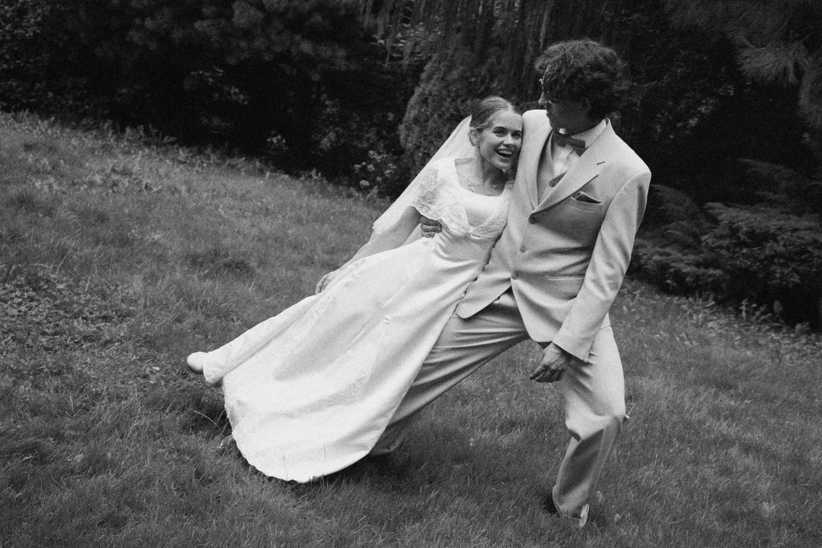 Para młoda tańczy na trawie podczas sesji ślubnej, romantyczny taniec w plenerze.