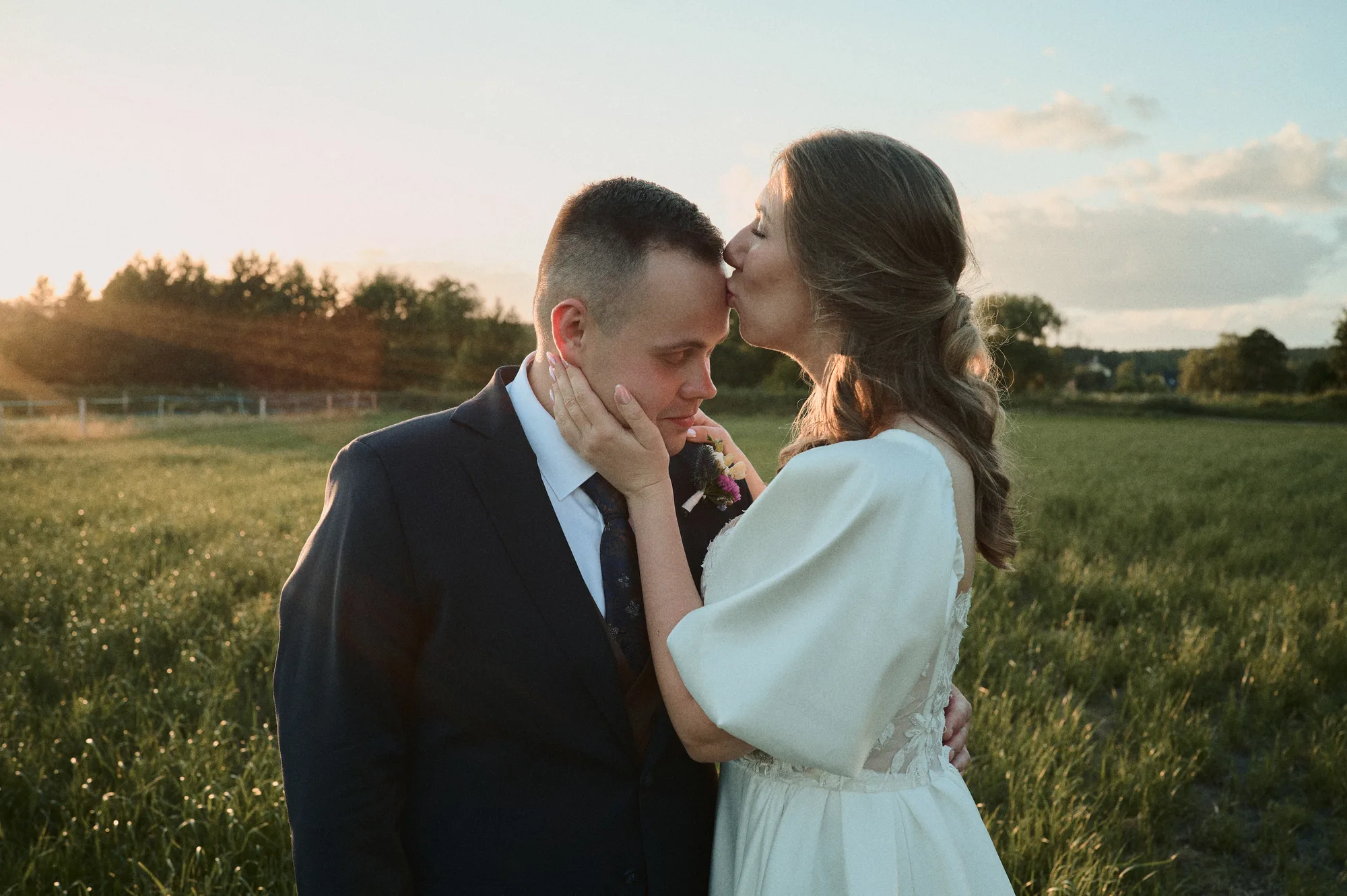 Czułe spojrzenia pary młodej w zachodzącym słońcu na polu.