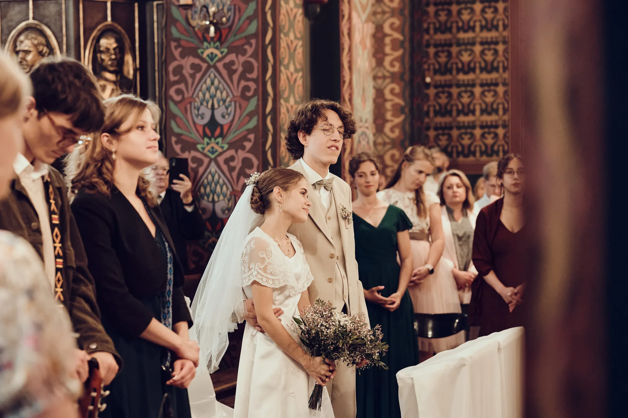 Goście weselni obserwujący ceremonię ślubną w kościele.