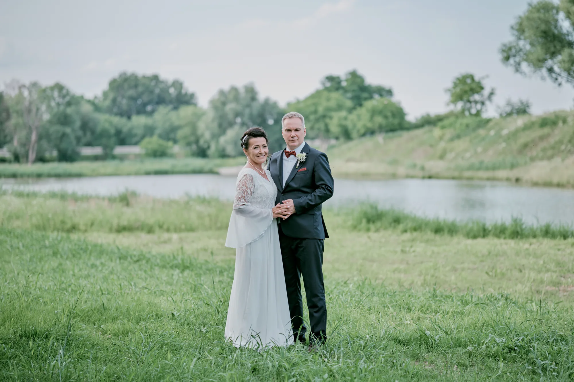Para młoda na tle jeziora i zieleni, ujęcie plenerowe.