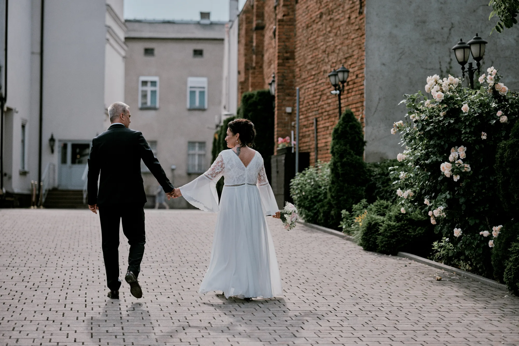 Para młoda spacerująca po zabytkowym dziedzińcu, ujęcie od tyłu.