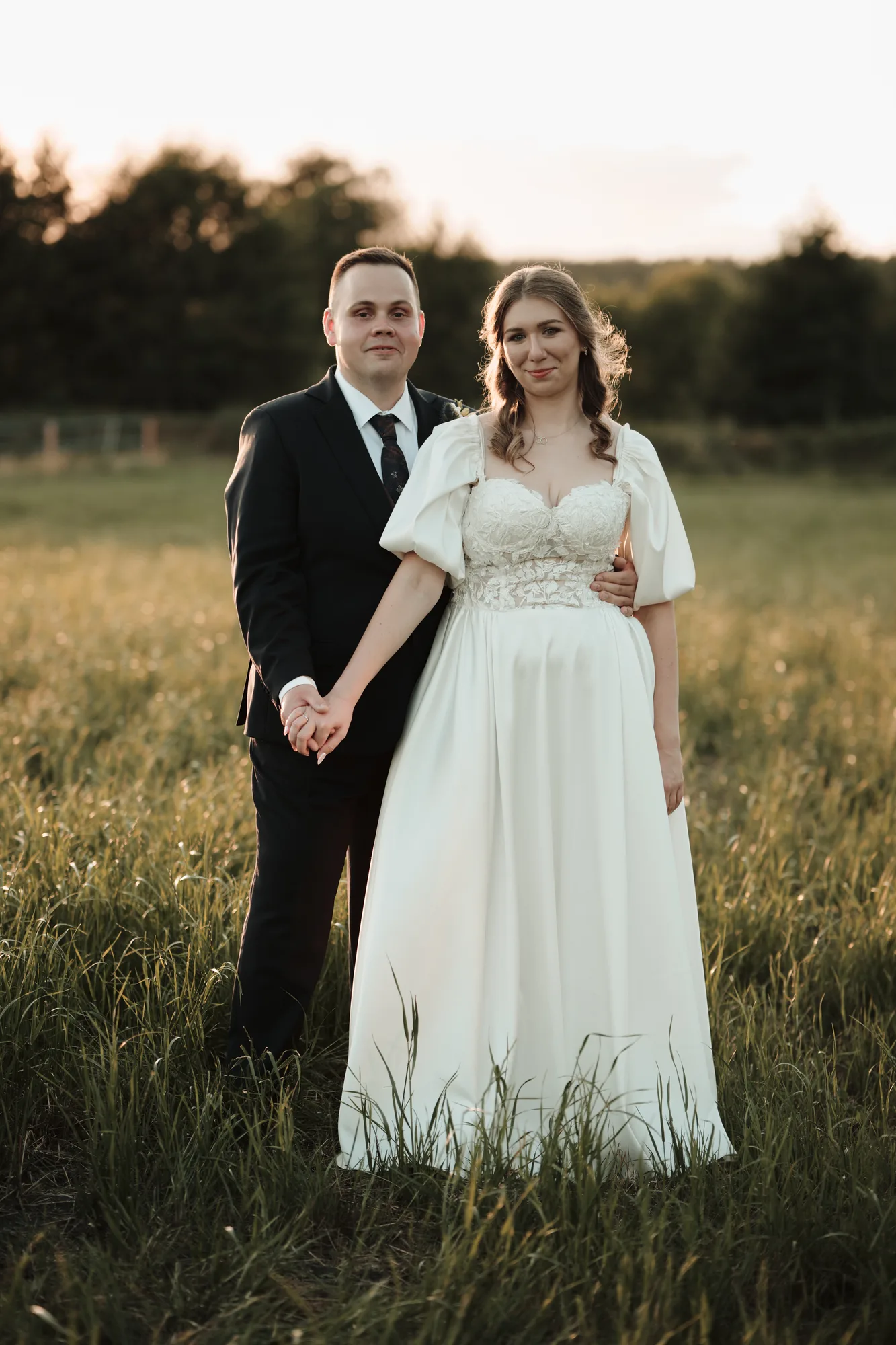 Para młoda trzymająca się za ręce na tle łąki.