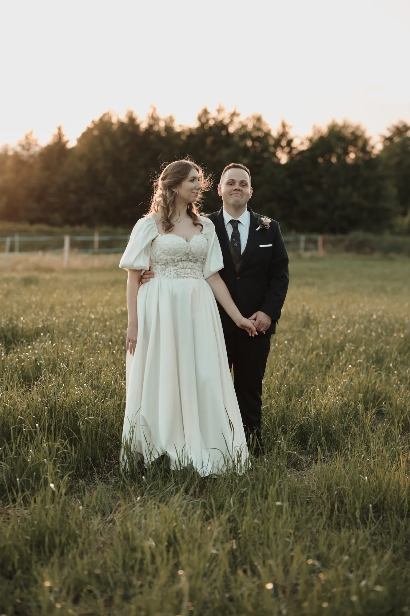 Sesja plenerowa pary młodej stojącej w wysokiej trawie na łące.
