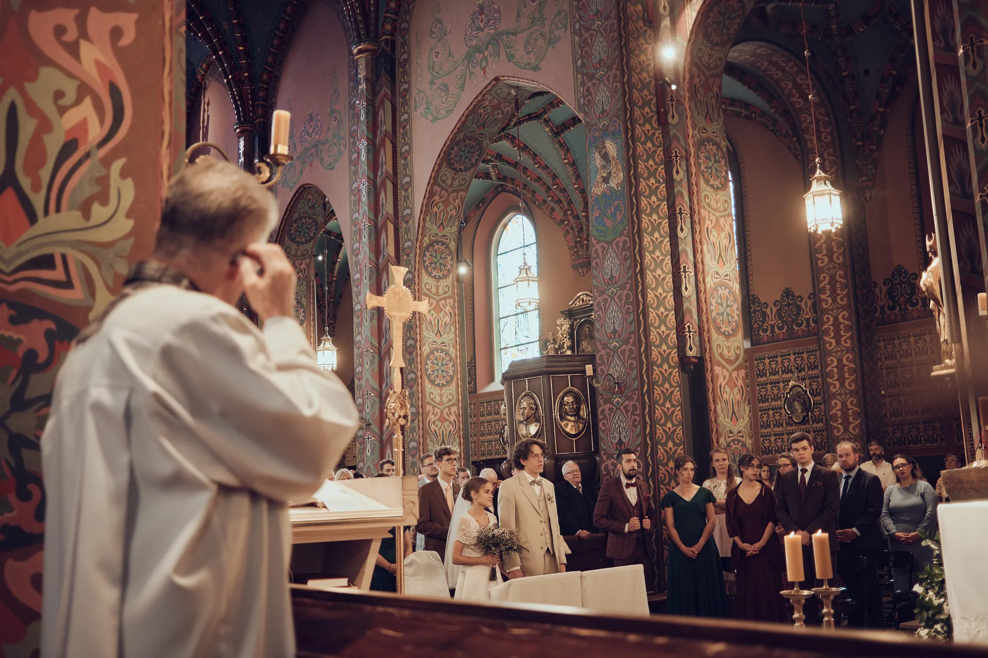 Wnętrze kościoła podczas ceremonii ślubnej, ksiądz przy ołtarzu.